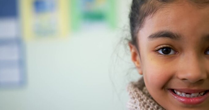 African American child with knit scarf turning to camera, showing gap smile at school, copy space