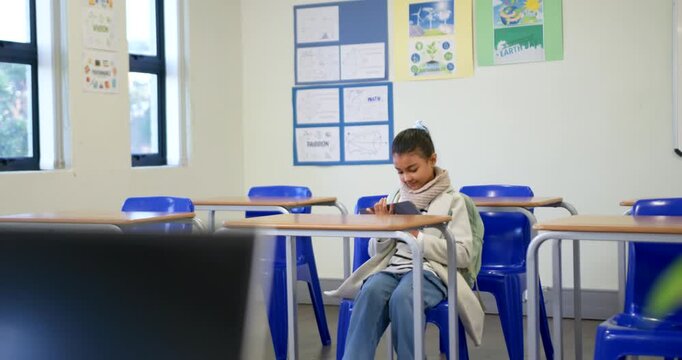 African American teenage student smiling and tapping tablet, reacting to on-screen content at desk