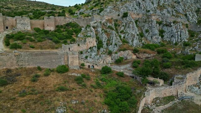 Aerial view of the ancient stone walls and historic fortifications of Acrocorinth fortress situated on a rocky hill in Greece.