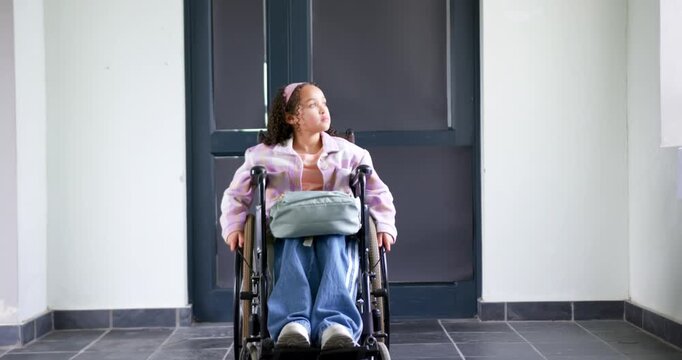 African-American teen girl sitting in wheelchair with bag scanning door as camera pulling waiting