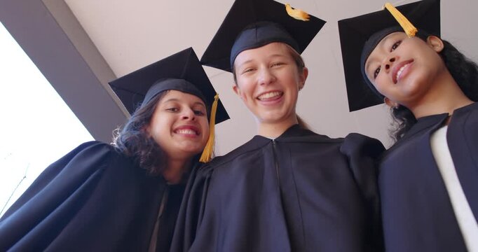 Female grads with child at door wearing gowns gold tassel caps raising rolled diplomas celebrating