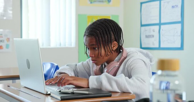 Youth student typing on laptop at school with headphones, finishing classwork and dozing