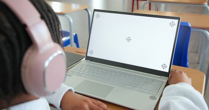 Male youth sitting at school using laptop with alignment marks, adjusting grip on edge, copy space