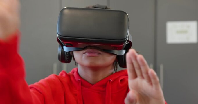 African American youth in red hoodie black VR headset pinching swiping to interact at grey cabinets
