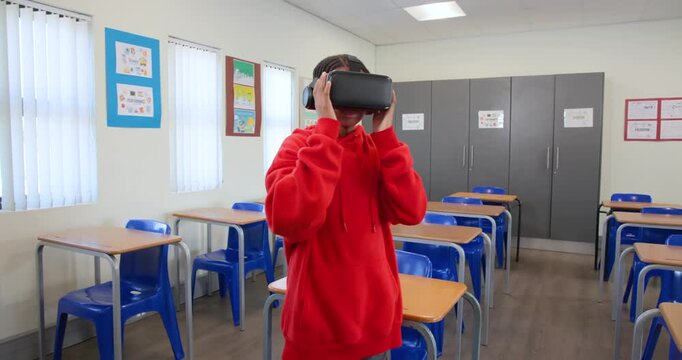 Male youth putting on VR headset adjusting straps, reaching and exploring virtual world in class