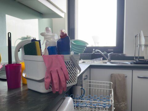 Cleaning supplies on kitchen counter with gloves and spray bottles