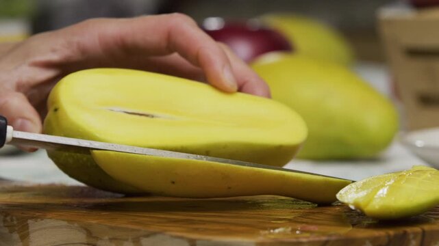 Slow motion shot of knife slicing mango and cutting squares in slice