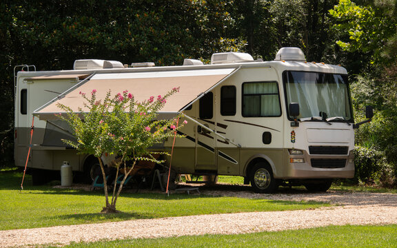 Rv parked at campsite on green grass with trees
