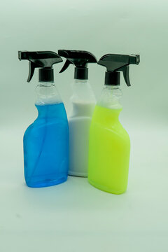 Different colors of cleaning spray bottles arranged on a neutral background