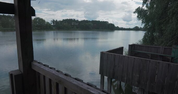 Beautiful panoramic view of rain drops falling on river water from wooden shelter