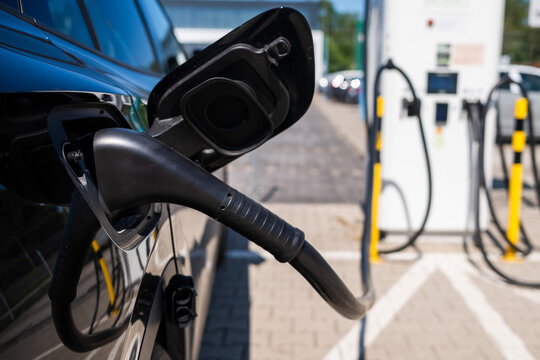 Electric vehicle charging at public charging station with charging cable connected, showcasing sustainable transportation, renewable energy and modern electric mobility technology.