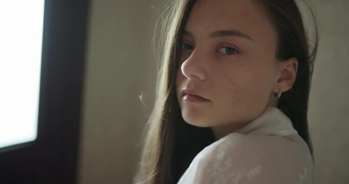 Close up portrait of beautiful young woman turning to look at camera, slow motion