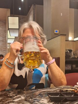 retired senior woman drinking a beer in a restaurant
