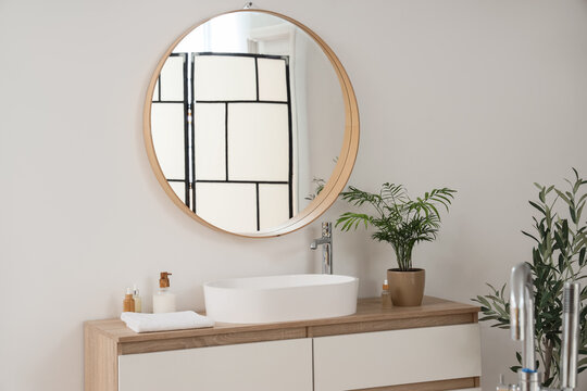 Sink with cosmetic products and palm on drawers in bathroom