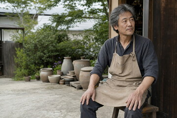 Fototapeta premium 陶芸工房の外で腰掛ける男性職人のポートレート