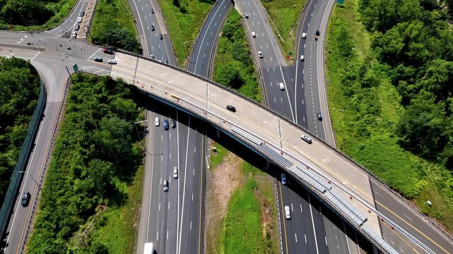 Aerial view of highway interchange traffic moving through green landscape, representing transportation, infrastructure, mobility, and connectivity.