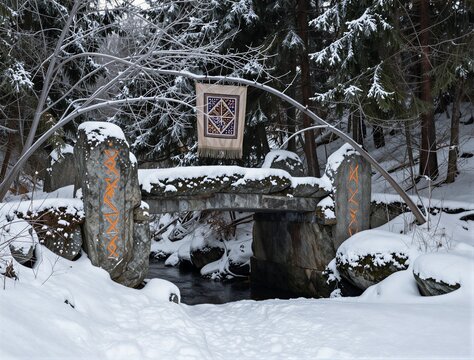 Stone rune pillars supporting small bridge in snowy forest