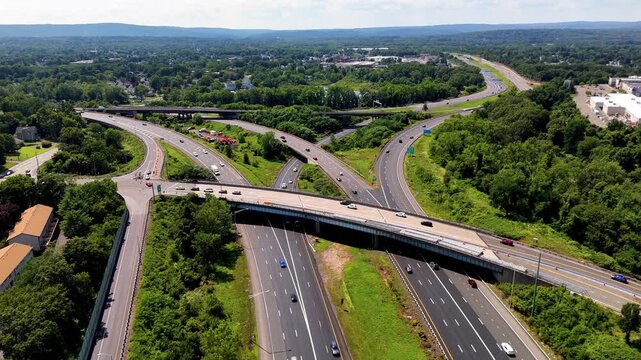 Aerial drone view of a busy highway interchange with vehicles traveling through multiple overpasses and connecting roads. Ideal for transportation, infrastructure, commuting, and traffic concepts.
