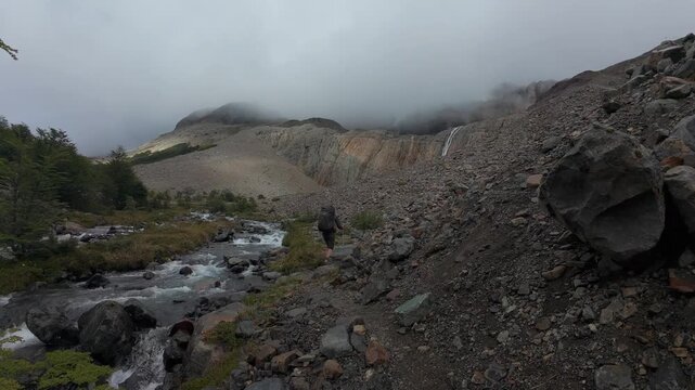 Backpacker Hiking Through Rocky Valley Along Mountain Stream In Cerro Castillo National Park Patagonia Chile