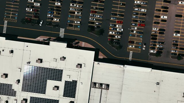 Drone view of an expansive parking lot with rows of parked cars and clearly marked spaces near city streets, symbolizing urban planning, transportation, and accessibility.