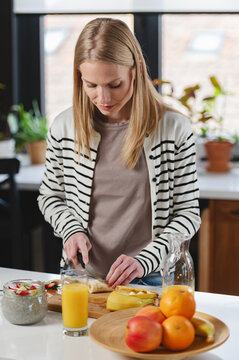 Woman preparing breakfast in a bright contemporary kitchen before starting the day. Homemade food, healthy nutrition, modern lifestyle, daily routine and wellness at home