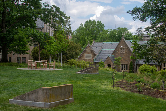 Washington, District of Columbia, United States - 06 May 2025: View of Washington National Cathedral grounds featuring stone architecture, green lawns, and outdoor seating under a cloudy sky.