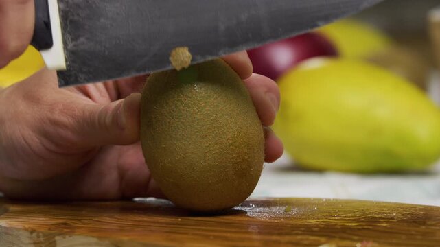 Extreme closeup shot of large knife shaving skin off kiwi in slow motion