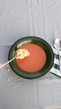 Hand adding chopped egg to traditional Spanish salmorejo soup