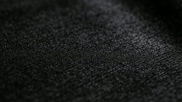 Abstract black fabric texture close-up, soft dark textile surface background, with subtle light, reflection and woven pattern