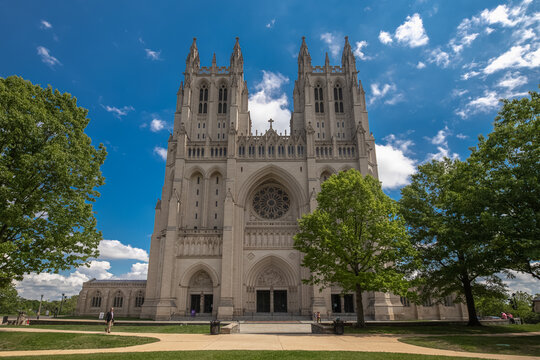 Washington, District of Columbia, United States - 06 May 2025: View of Washington National Cathedral with intricate Gothic architecture, stone facade, and rose window under a blue sky.