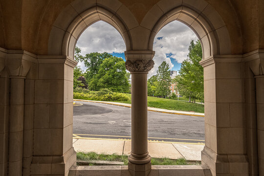 Washington, United States - 06 May 2025: View of Washington National Cathedral through stone arches with a view of the surrounding grounds and trees.