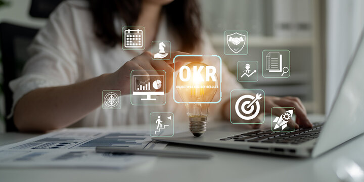 Business professional utilizing technology for OKR implementation with data visualization and strategic planning symbols in a modern workspace environment Fluxor.