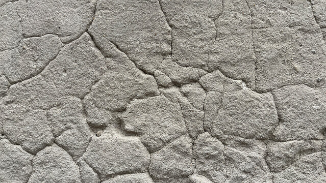 Close‑up of cracked roughcast plaster wall with irregular stucco patches and visible fissures, creating an abstract textured background with weathered architectural character.