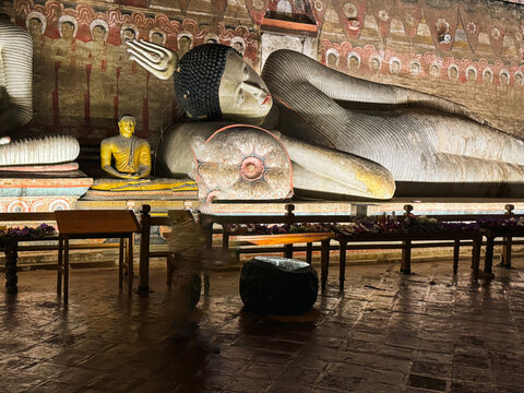 Sri Lanka - 20 April 2024: View of the ancient reclining Buddha statue inside the Dambulla Cave Temple, featuring intricate wall paintings and warm lighting.