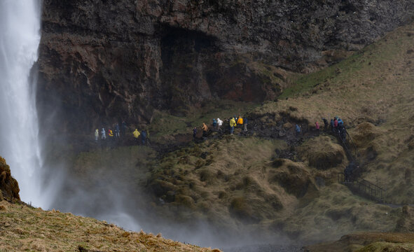 Tourist people walking behind seljalandsfoss waterfall in iceland