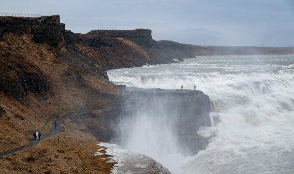 Gullfoss waterfall showing tourists observing the powerful cascading water of the hvita river in iceland golden circle