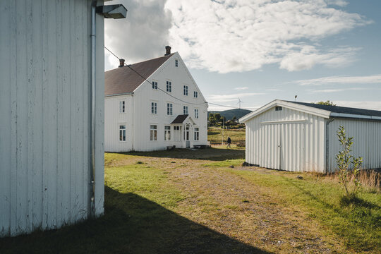 Jennestad, Norway - 31 August 2025: View of the historic white wooden trading post building in Jennestad with a grassy yard and outbuildings under a blue sky.