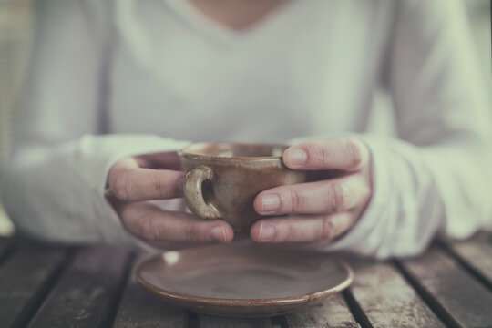 Close-up of a Woman sitting at a table holding a cup of coffee