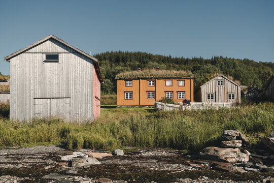 Straumsgard, Troms, Norway - 29 August 2025: View of traditional wooden houses with grass roofs and a grey barn in a coastal setting.