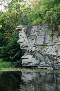 Steep Rocky Canyon Cliffs with Trees and Water Reflection