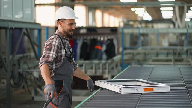 Factory worker assembling pvc window frame on production line