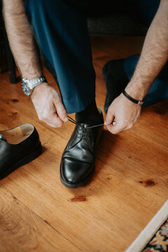 Homme en costume la&ccedil;ant ses chaussures en cuir noir avant une c&eacute;r&eacute;monie de mariage