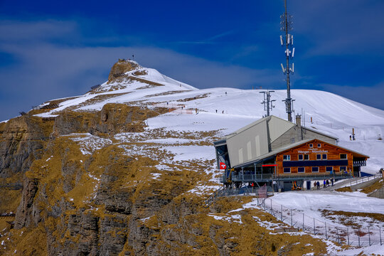 Mannlichen, Grindelwald, Switzerland - 13.03.2026. A striking winter landscape showcasing the wooden Wengen-M&auml;nnlichen cable car station and a tall communication tower perched on a steep alpine ridge 