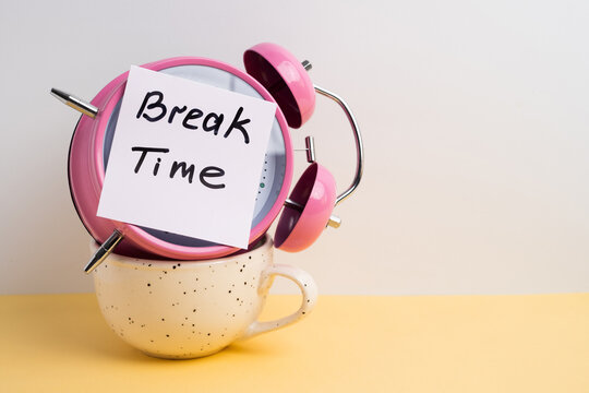 Pink alarm clock in a coffee cup with a Break Time note for work-life balance concept	