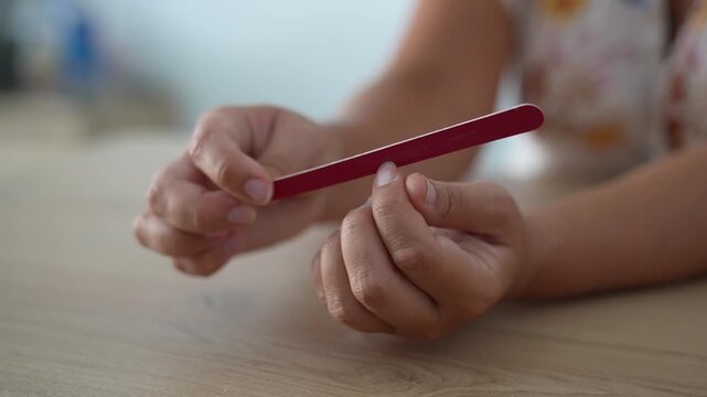 Woman Filing Fingernails with Nail File During Home Manicure