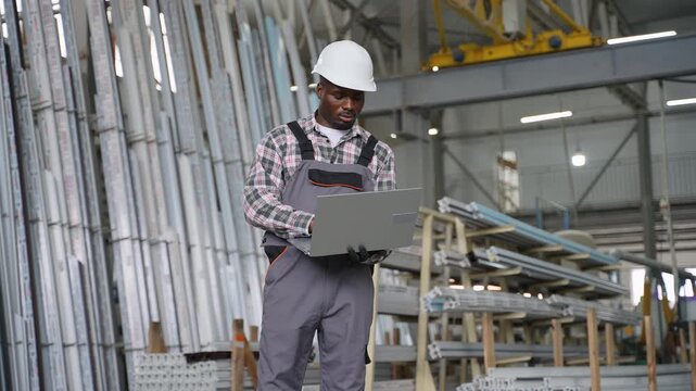 African American male warehouse worker using laptop for inventory control