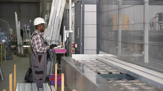 African american worker operating industrial cnc machine