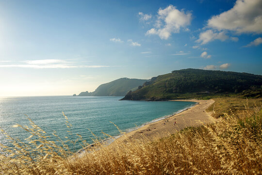 Idyllic summer landscape a sandy beach in sea cove, on the background of green mountains and blue sky, Fisterra, northern Spain
