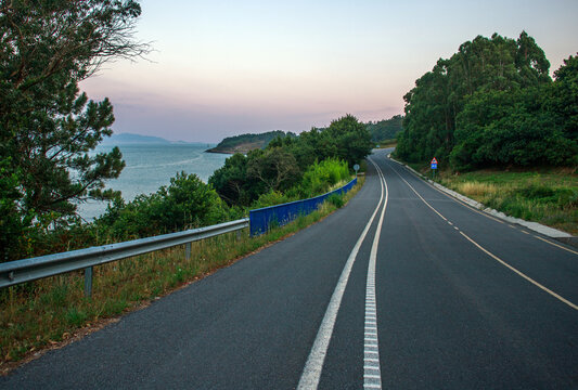 Evening landscape, paved road, highway, amidst forest on hill overlooking the seacoast, set against a twilight sky