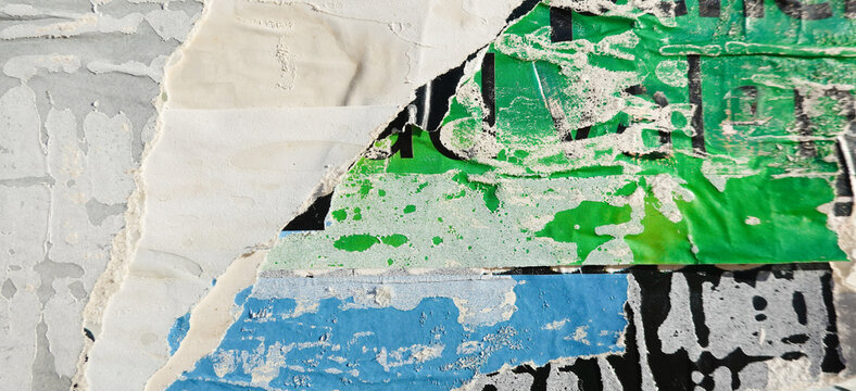 Old posters wall with layers of peeling placards in various colors including green, blue, and white colors
